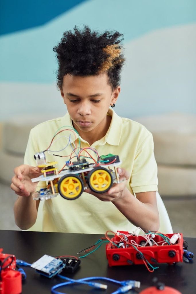 Young boy focuses on assembling a robotic project indoors, highlighting education and technology.