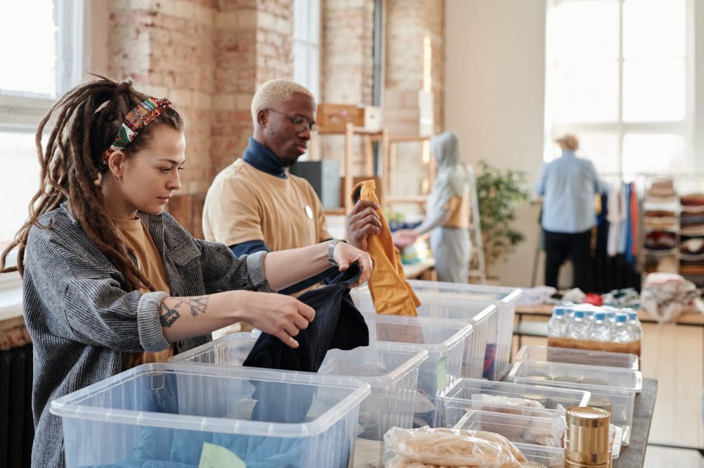 Volunteers organize donated clothing at a donation center, fostering community support and sustainability.